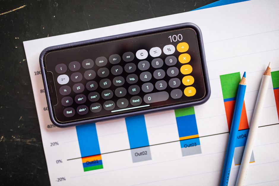 Calculadora móvel em gráficos de papel indicando análise financeira com visualização de dados coloridos.