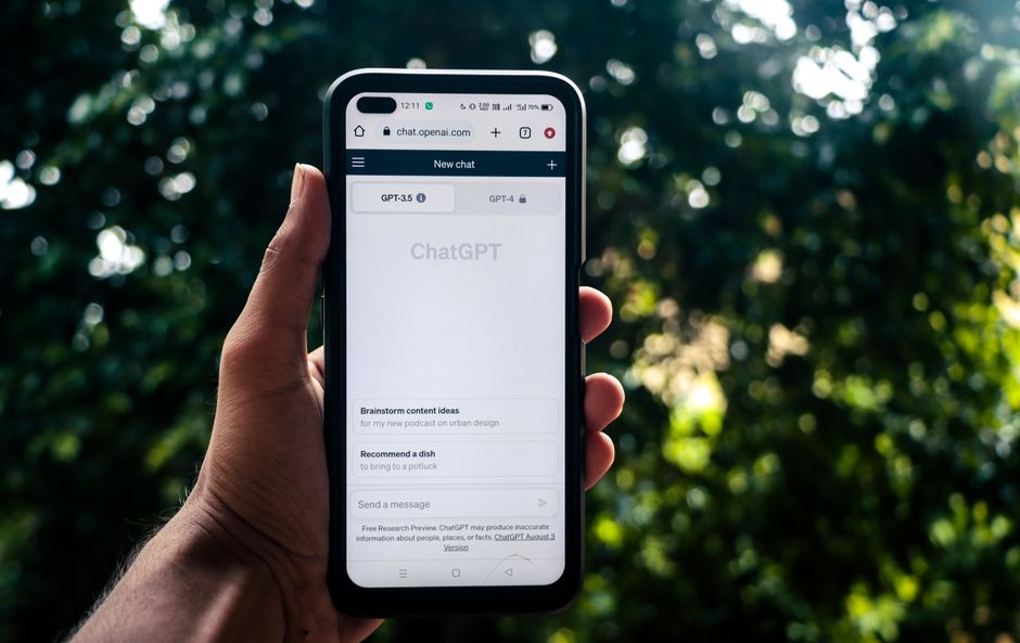 Uma pessoa usa o ChatGPT em um smartphone ao ar livre, mostrando a tecnologia no dia a dia.