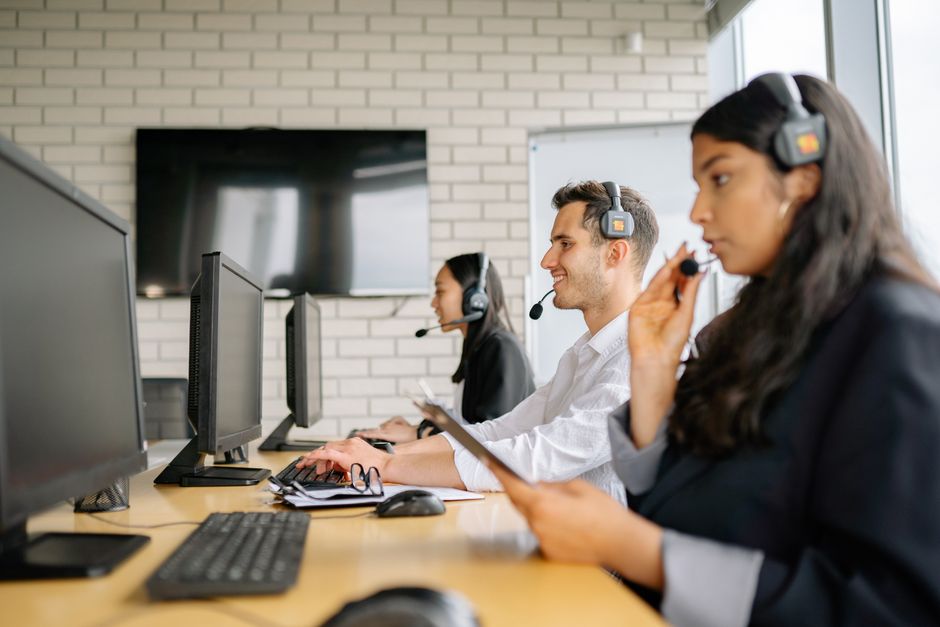 Grupo diversificado de agentes de call center trabalhando juntos em um ambiente moderno de escritório.