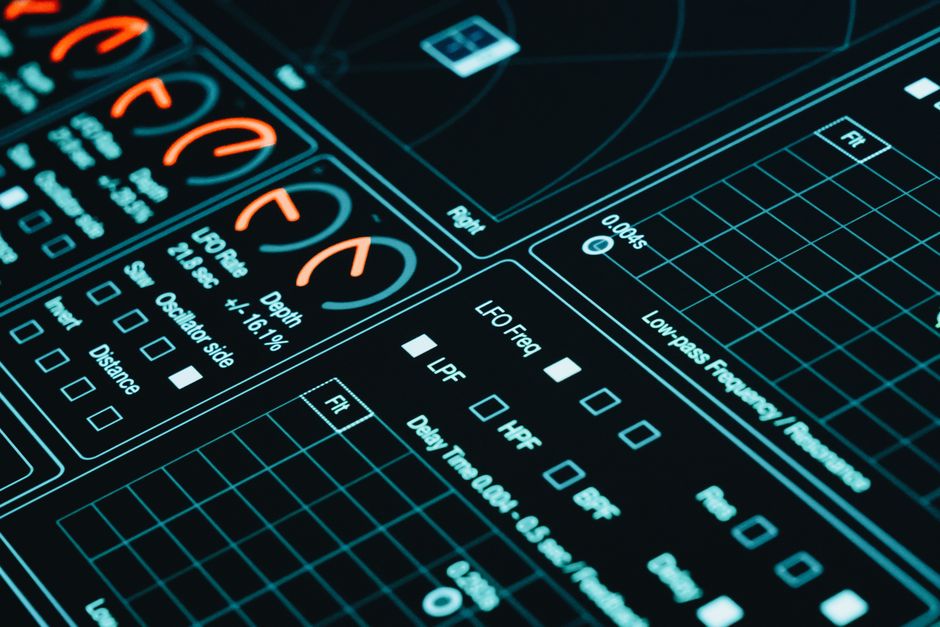 Close-up de uma interface digital exibindo gráficos futuristas e análises de dados em baixa luminosidade.