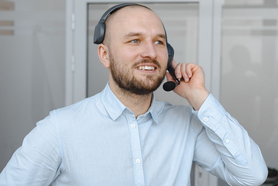 Agente de call center sorridente usando um headset fornecendo atendimento ao cliente em um ambiente de escritório.